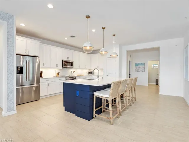 a kitchen with stainless steel appliances kitchen island granite countertop a table chairs and a refrigerator