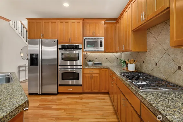 a kitchen with stainless steel appliances granite countertop a stove a sink and a refrigerator