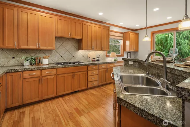 a kitchen with stainless steel appliances granite countertop a sink a stove and cabinets