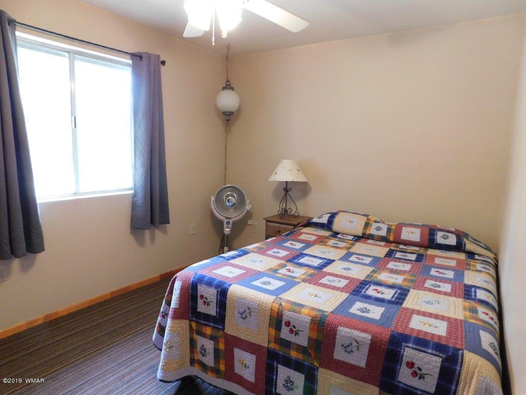 2136 Cottontail Road Overgaard, AZ 85933 - Photo 22 of 23 a bedroom with a bed a lamp and a large window