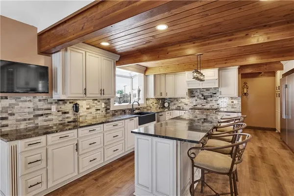 a kitchen with stainless steel appliances kitchen island granite countertop a stove a sink and white cabinets with wooden floor