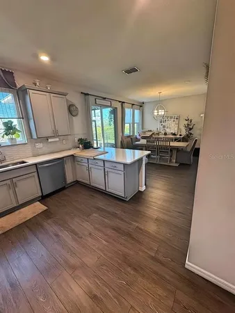 a living room with couches and kitchen view with wooden floor