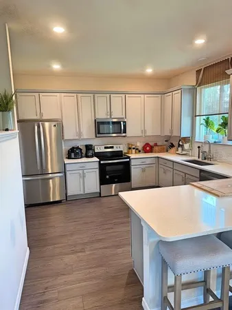 a kitchen with kitchen island a counter top space a refrigerator a stove a sink and cabinets