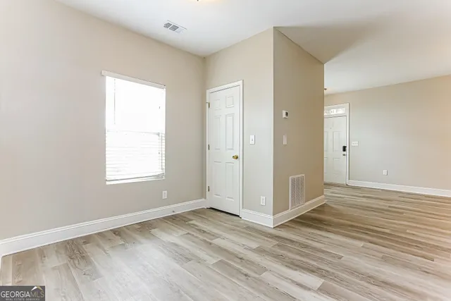 an empty room with wooden floor and windows