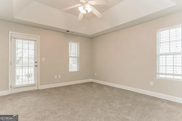 an empty room with windows and chandelier fan