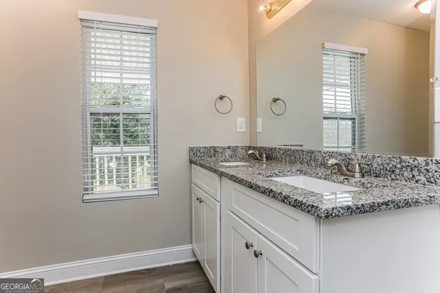 a bathroom with a granite countertop sink and a window