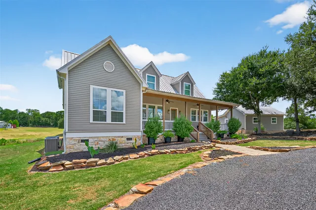a front view of a house with garden and trees