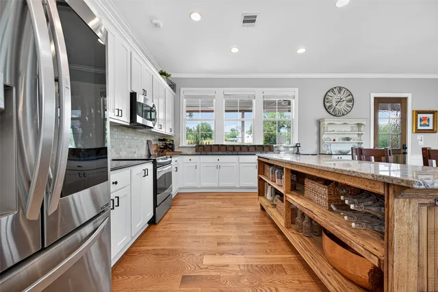 a large kitchen with stainless steel appliances a large counter top a stove and a sink