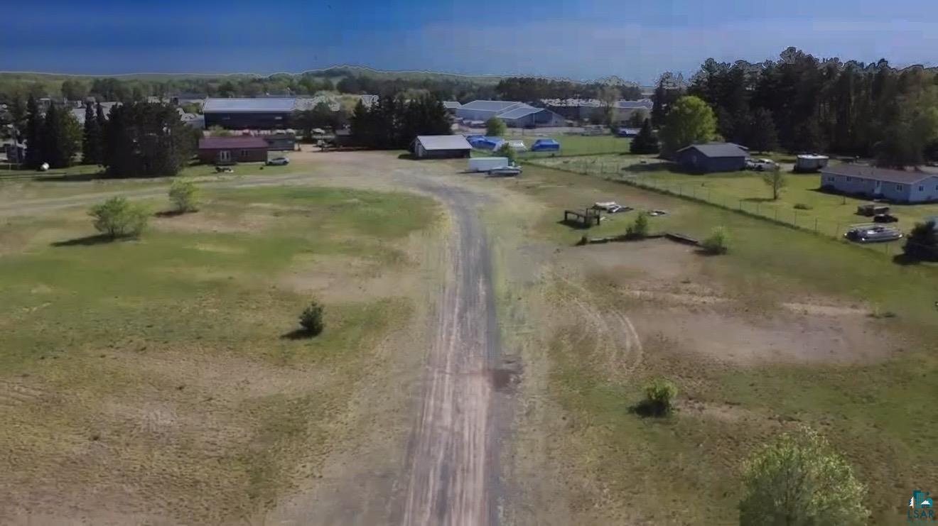 620 Shell Creek Road Minong, WI 54859 - Photo 29 of 33 Expansive open lot with a central unpaved driveway, surrounded by mature trees and verdant landscaping
