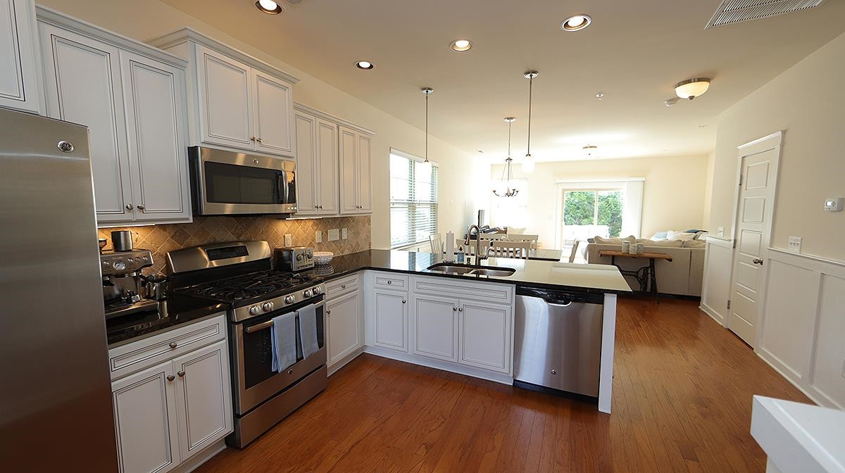 6414 Swatner Drive Raleigh, NC 27612 - Photo 4 of 21 Kitchen Amenities include Custom Backsplash, Stainless Steel Appliances, Built in Microwave, Striking Black Granite with White Staggered Cabinets PLUS a Combination of Pendant and Can Lighting. Kitchen Amenities
