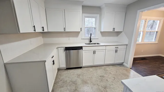 a kitchen with white cabinets sink and window