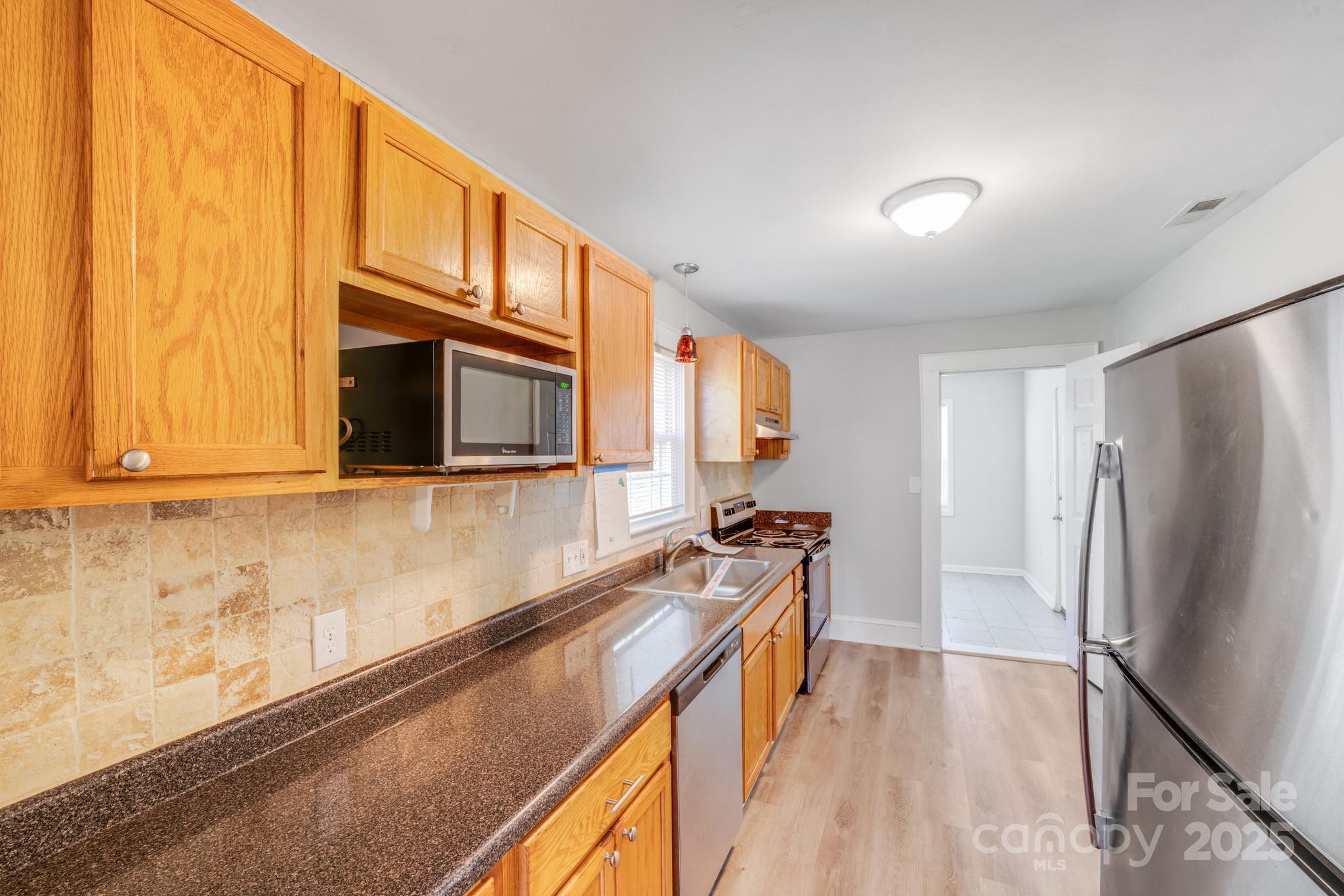 3138 Morson Street Charlotte, NC 28208 - Photo 9 of 21 a kitchen with stainless steel appliances a microwave a stove and a refrigerator