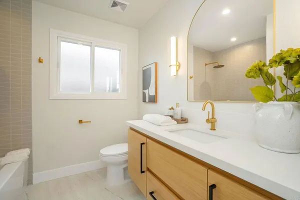 a bathroom with a granite countertop sink a toilet and a mirror