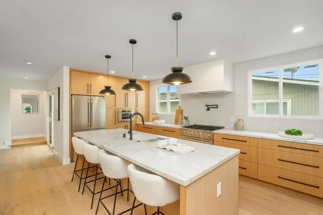 a kitchen with stainless steel appliances kitchen island a table chairs in it and wooden floors