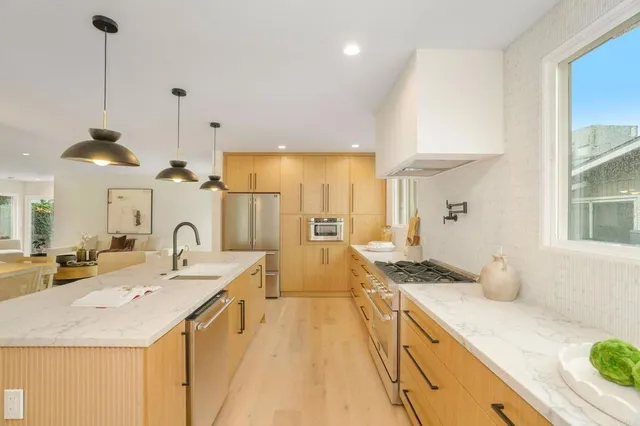 a large kitchen with kitchen island a large counter space a sink stainless steel appliances and cabinets