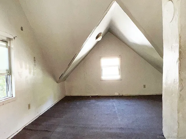 a view of an empty room with wooden floor and windows