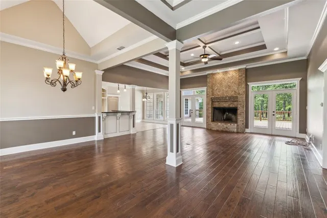 a view of an empty room with wooden floor fireplace and a window