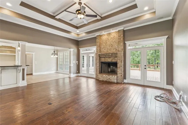 a view of an empty room with wooden floor fireplace and a window