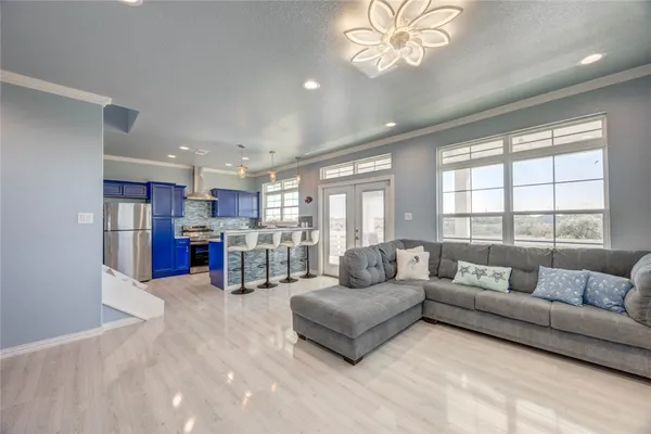 a living room with furniture and a large window with kitchen view