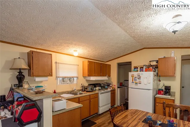 a white kitchen with a sink dishwasher stove and refrigerator