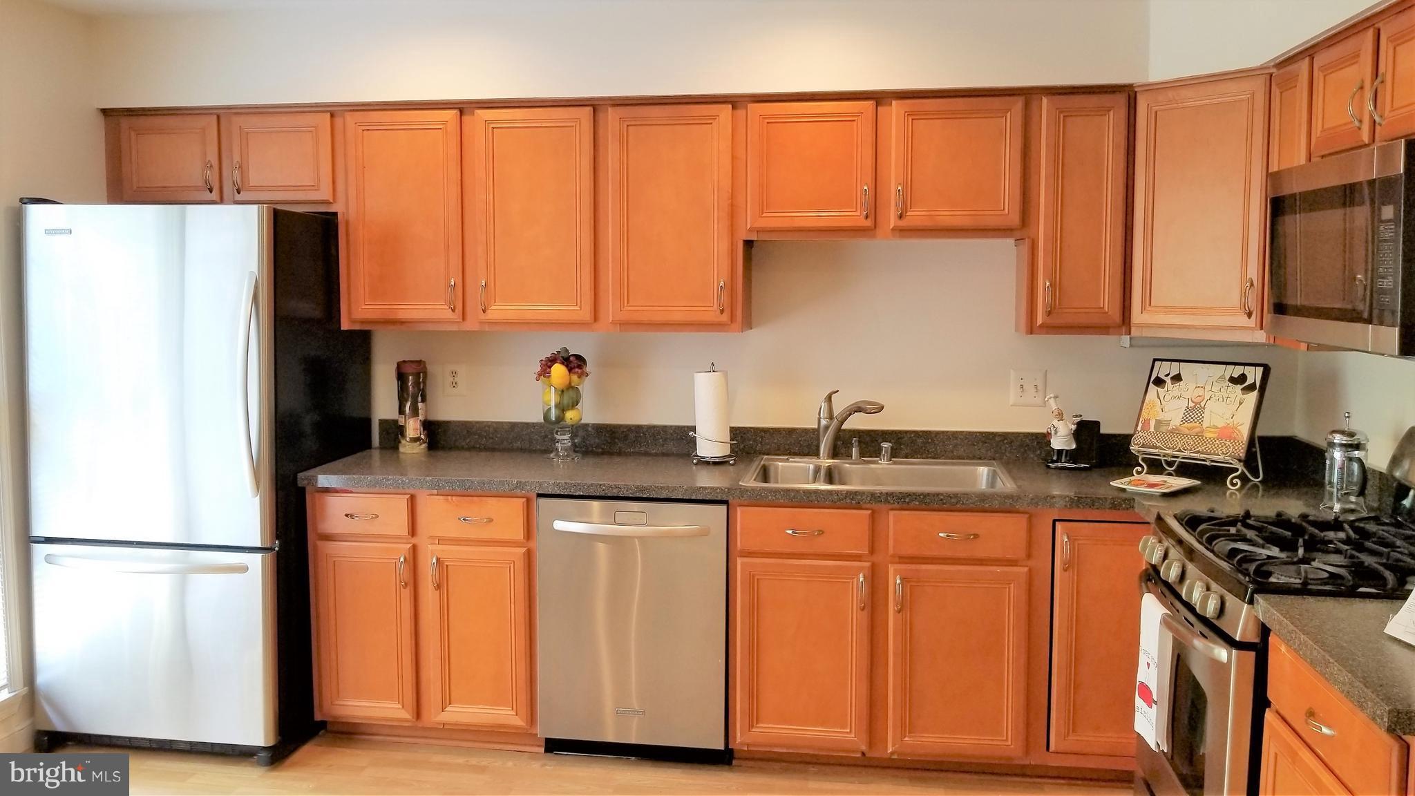 10955 Rocky Mt Way Silver Spring, MD 20902 - Photo 6 of 30 a kitchen with stainless steel appliances granite countertop a refrigerator a sink a stove and white cabinets