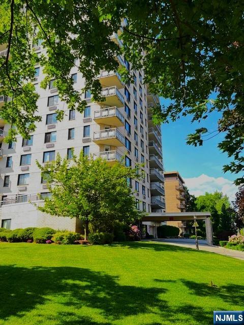 a view of a white house with a big yard and potted plants and large trees