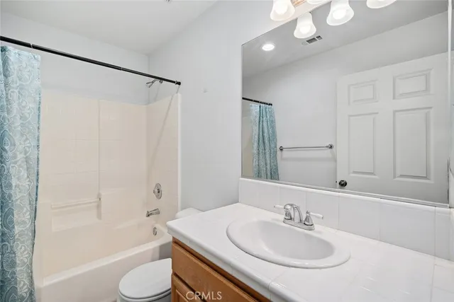 a bathroom with a sink a toilet a mirror a bathtub and shower