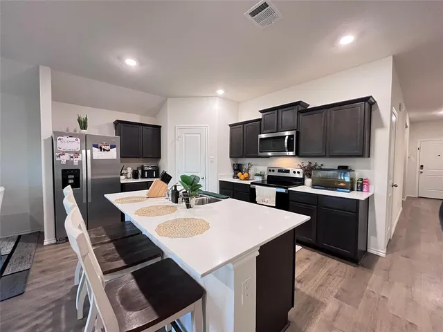 a large kitchen with kitchen island a sink a counter top space and stainless steel appliances