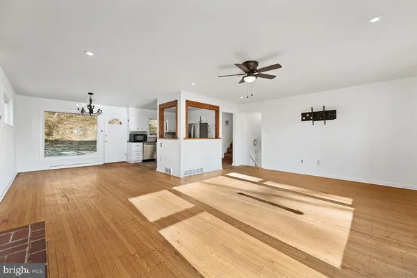 a view of an empty room with a window and wooden floor