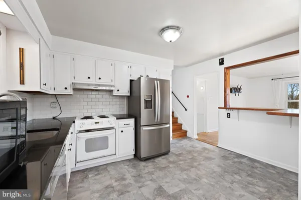 a kitchen with white cabinets stainless steel appliances and a window