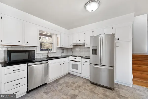 a kitchen with granite countertop white cabinets and white appliances