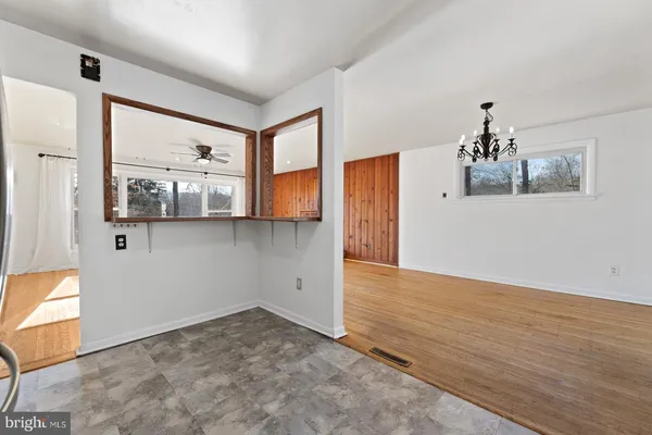 a view of an empty room with wooden floor and a ceiling fan