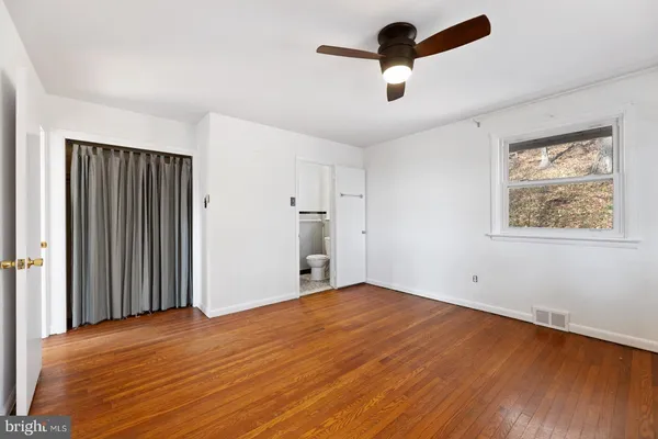 an empty room with wooden floor and ceiling fan