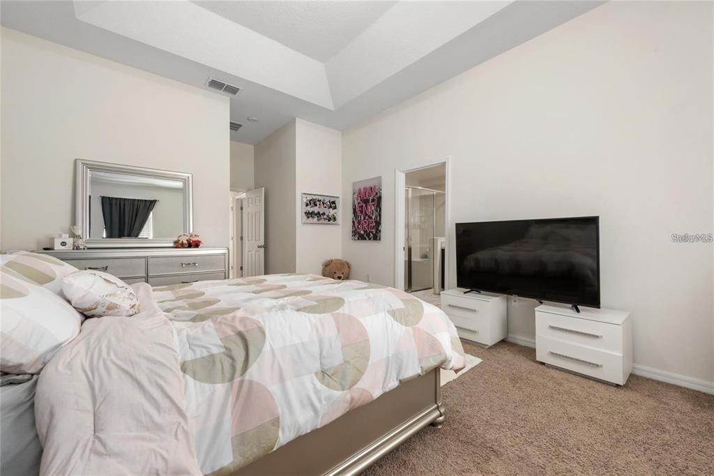 2449 Varenna Loop Kissimmee, FL 34741 - Photo 11 of 25 a bedroom with a bed and a flat screen tv