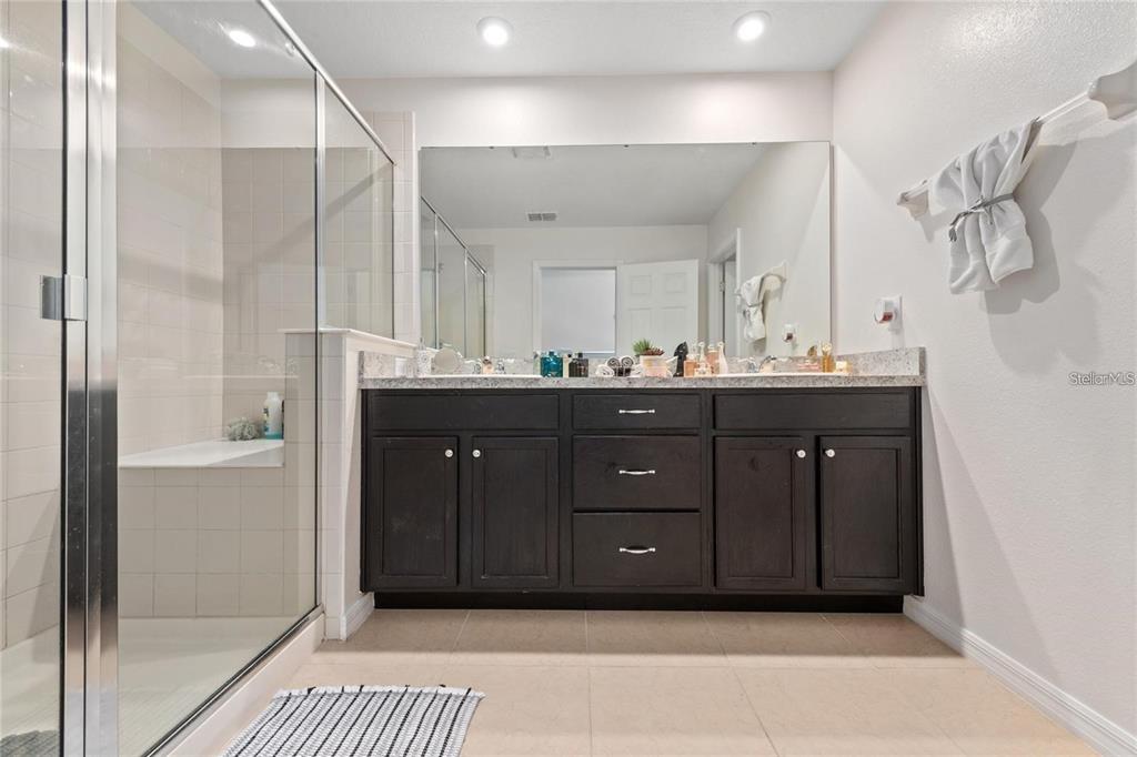 2449 Varenna Loop Kissimmee, FL 34741 - Photo 12 of 25 a bathroom with a granite countertop sink a mirror and a shower