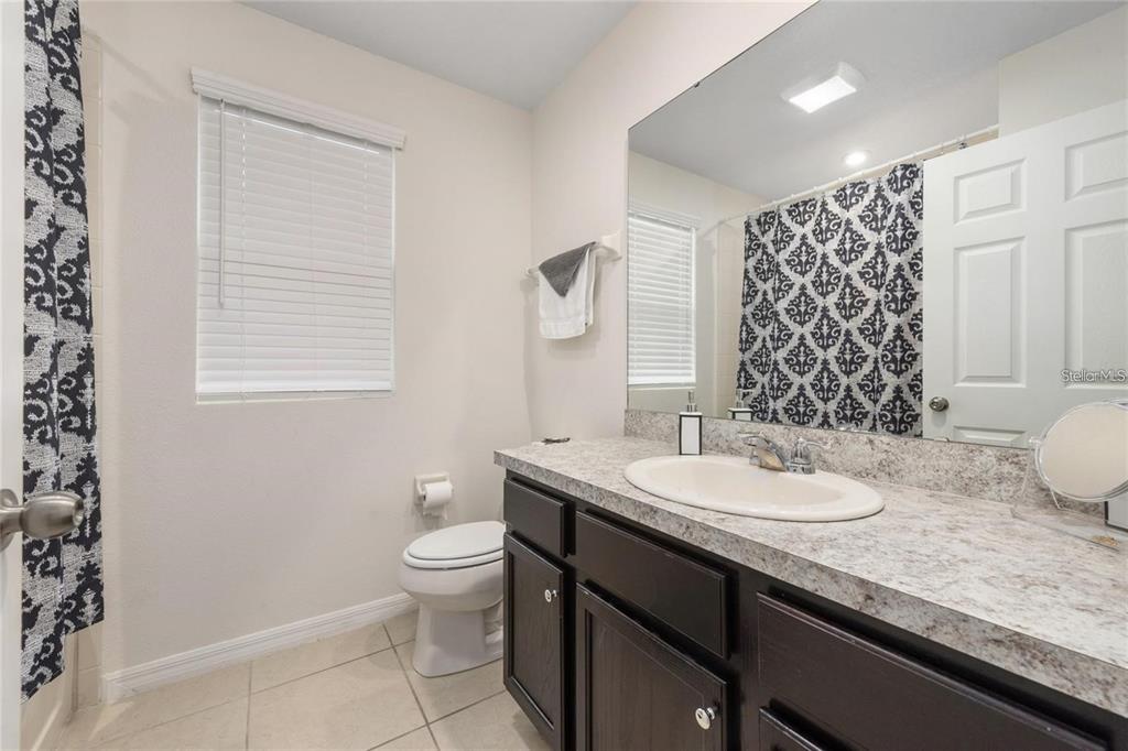 2449 Varenna Loop Kissimmee, FL 34741 - Photo 14 of 25 a bathroom with a granite countertop sink a toilet and a mirror