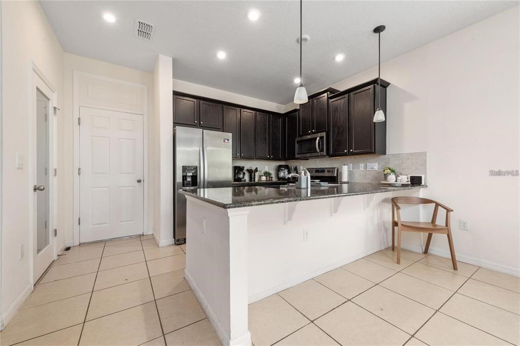 2449 Varenna Loop Kissimmee, FL 34741 - Photo 3 of 25 a kitchen with kitchen island granite countertop a stove a sink and a refrigerator with wooden cabinets