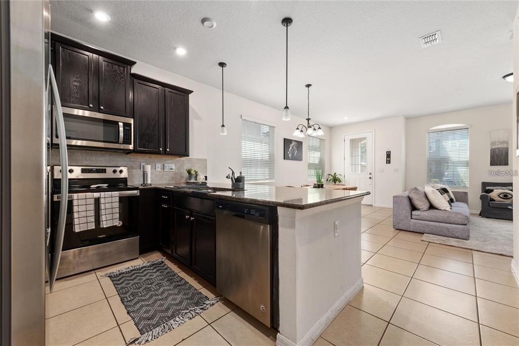 2449 Varenna Loop Kissimmee, FL 34741 - Photo 4 of 25 a kitchen with stainless steel appliances kitchen island granite countertop a sink and cabinets