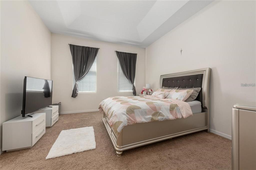 2449 Varenna Loop Kissimmee, FL 34741 - Photo 10 of 25 a bedroom with a bed flat screen tv and window