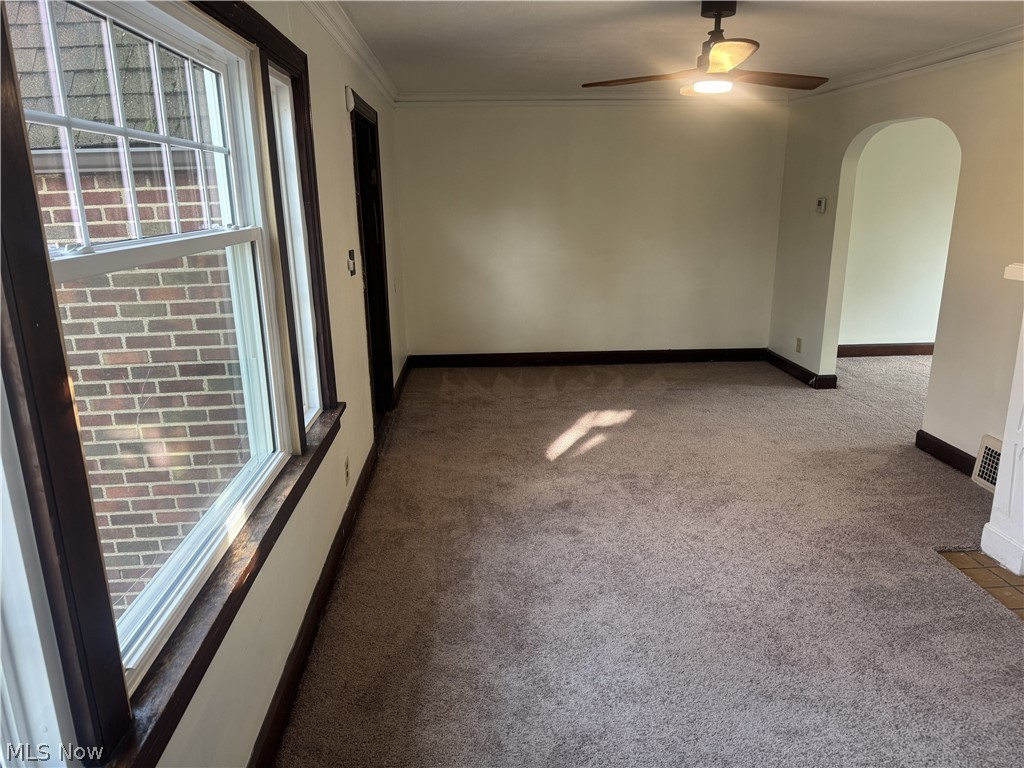 4058 Ardmore Road Cleveland, OH 44121 - Photo 4 of 14 Carpeted empty room featuring arched walkways, crown molding, and a ceiling fan