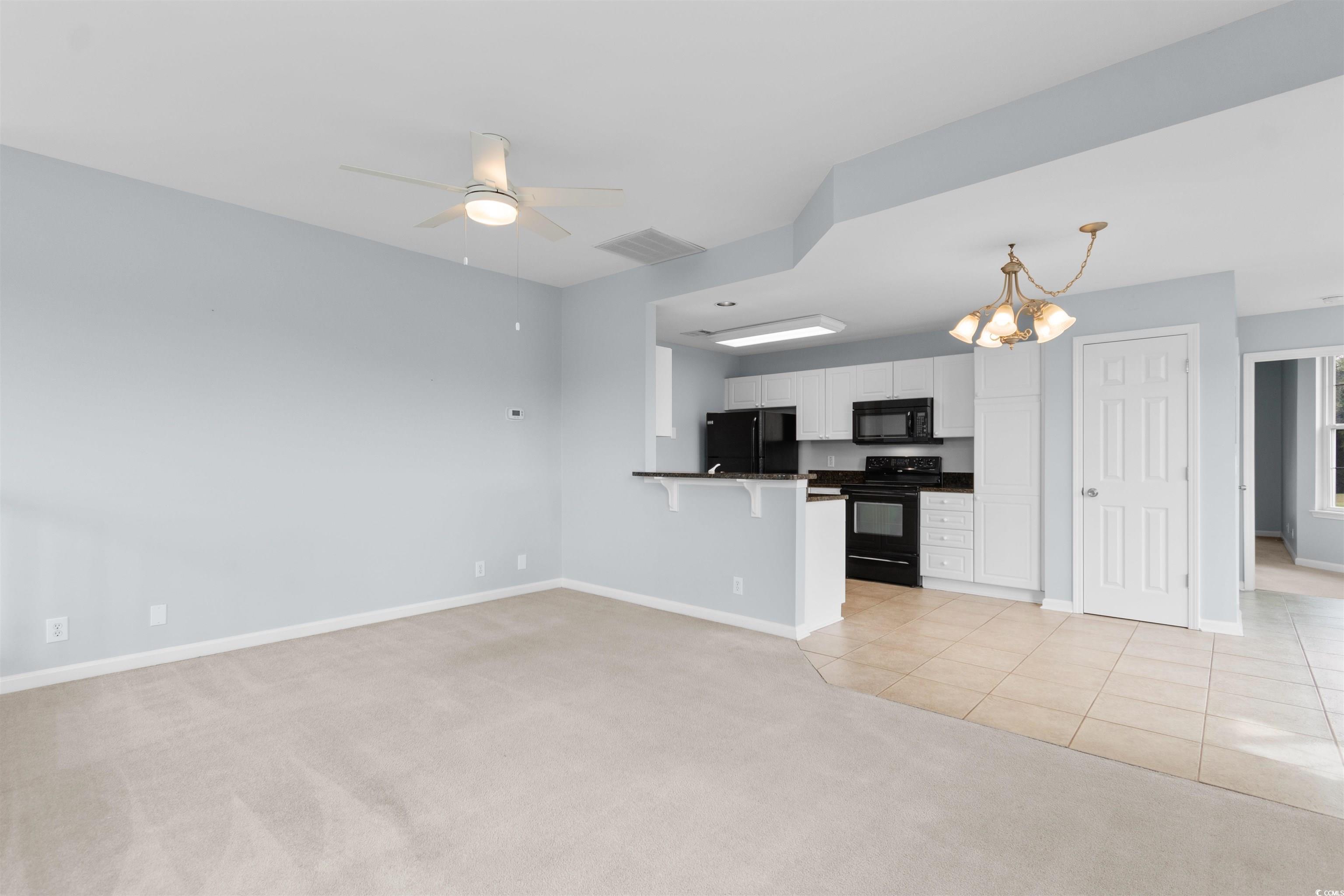 4430 Lady Banks Lane, Unit A2 Murrells Inlet, SC 29576 - Photo 5 of 31 Unfurnished living room with light carpet, a chandelier, light tile patterned floors, and ceiling fan