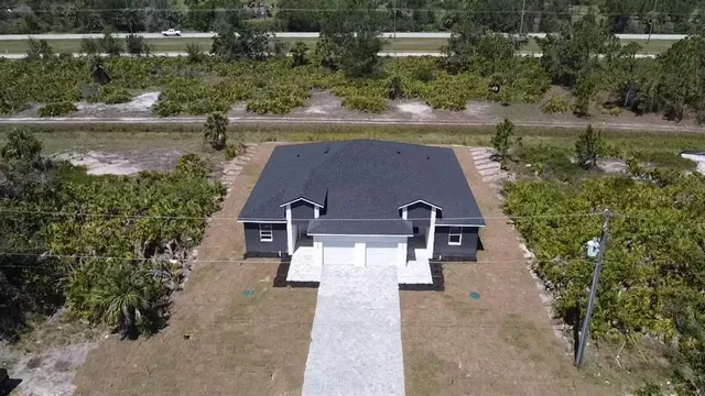 an aerial view of a house with a yard and large trees