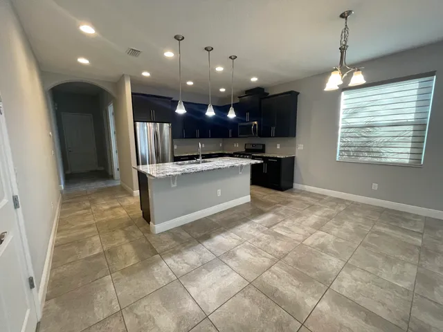 a open kitchen with kitchen island granite countertop a sink and a stove top oven