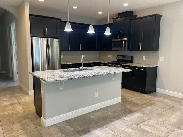 a kitchen with stainless steel appliances granite countertop a sink a stove a refrigerator and a microwave