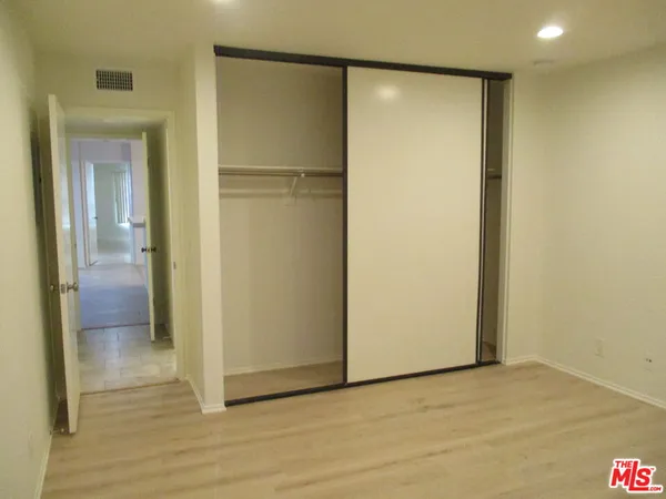 a view of an empty room with wooden floor and a bathroom