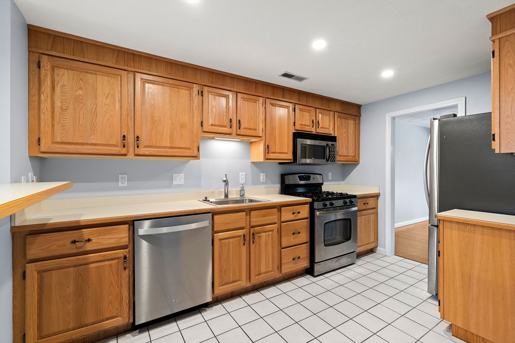 4 Iris Way, Unit 22 Haverhill, MA 01830 - Photo 21 of 38 a kitchen with stainless steel appliances granite countertop a sink stove refrigerator and cabinets