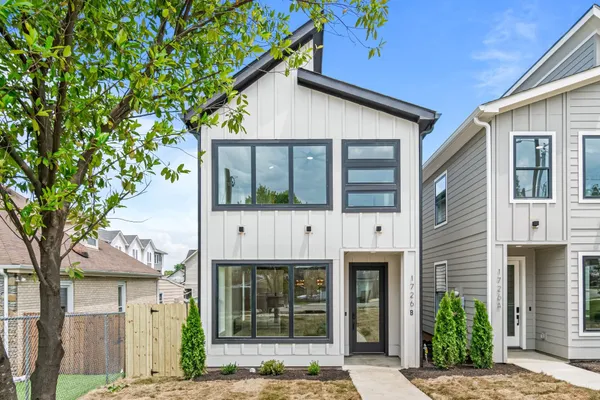 a view of a white house with large windows and a small yard