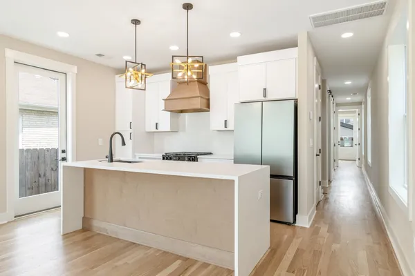 a kitchen with stainless steel appliances granite countertop a sink a refrigerator and a wooden floor