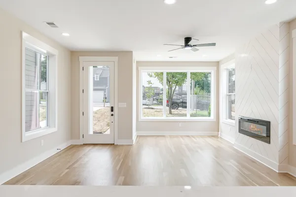 a view of an empty room with a window and wooden floor
