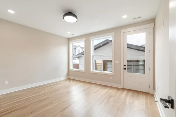 an empty room with wooden floor and windows
